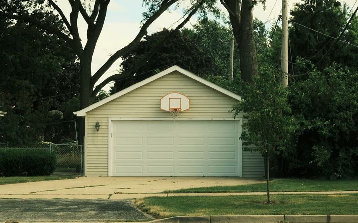 Basketball hoop mounted over a garage door at the end of a driveway