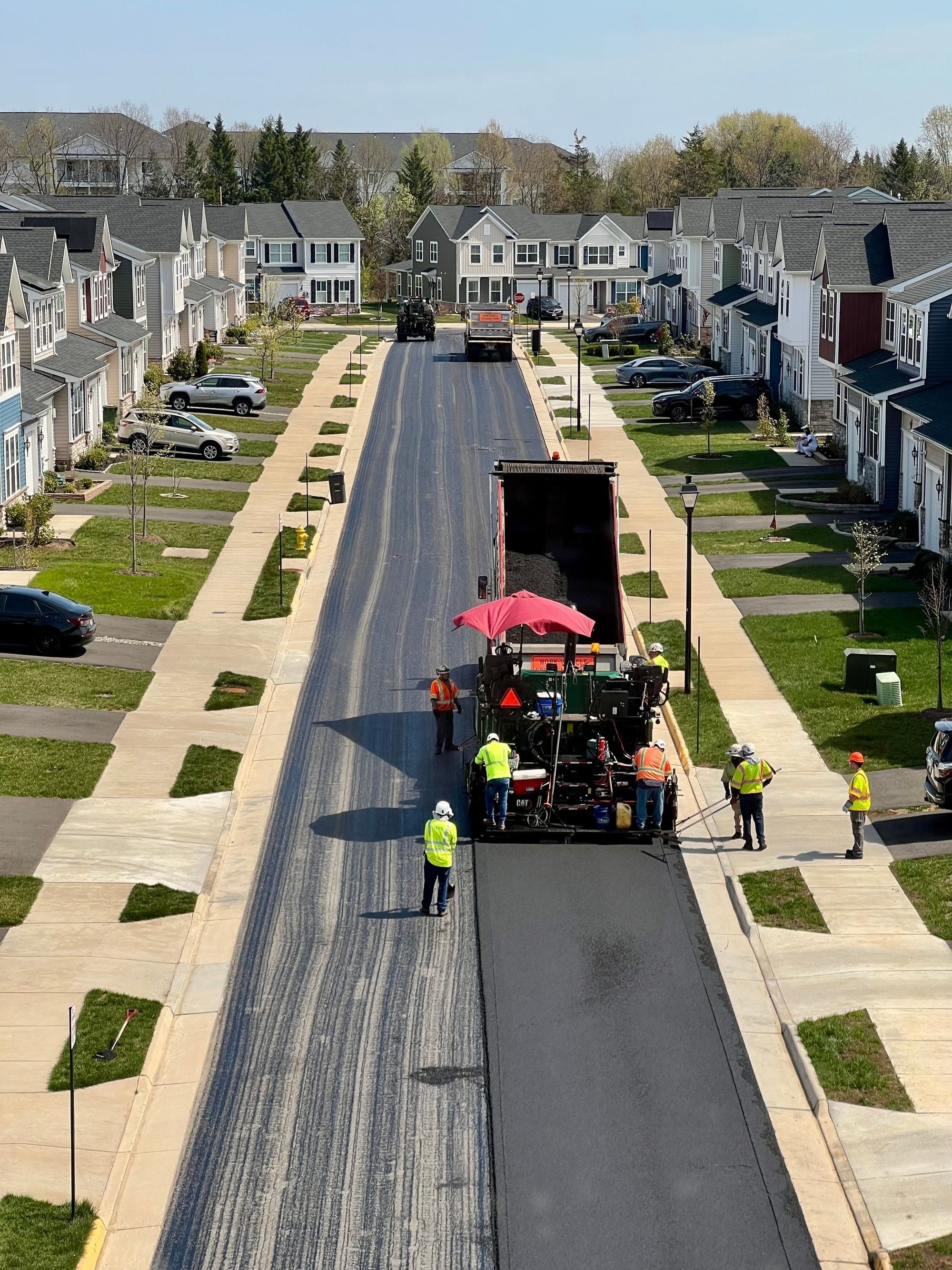 Paving crew laying new asphalt on a residential street lined with houses