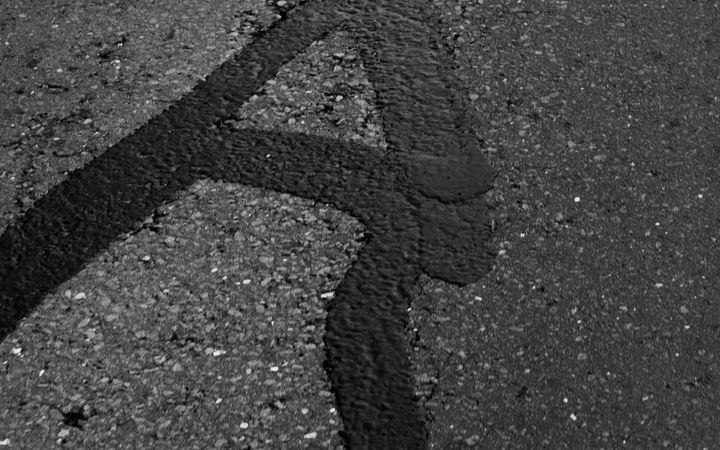 Crack in asphalt filled with a band of black sealant
