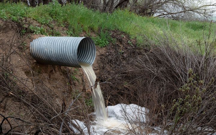 Corrugated metal culvert pipe draining water into a ditch