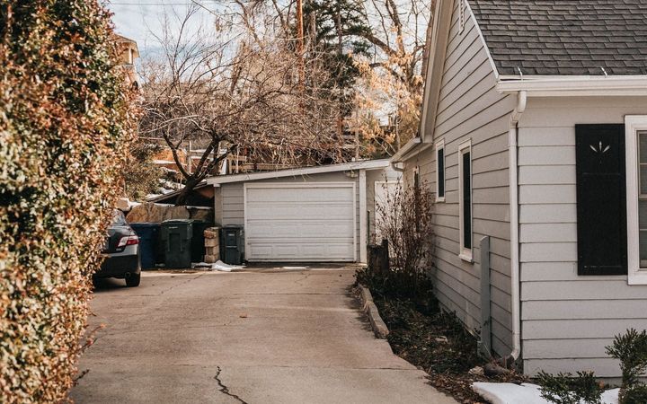 Cracked, worn driveway running past a house to a detached garage