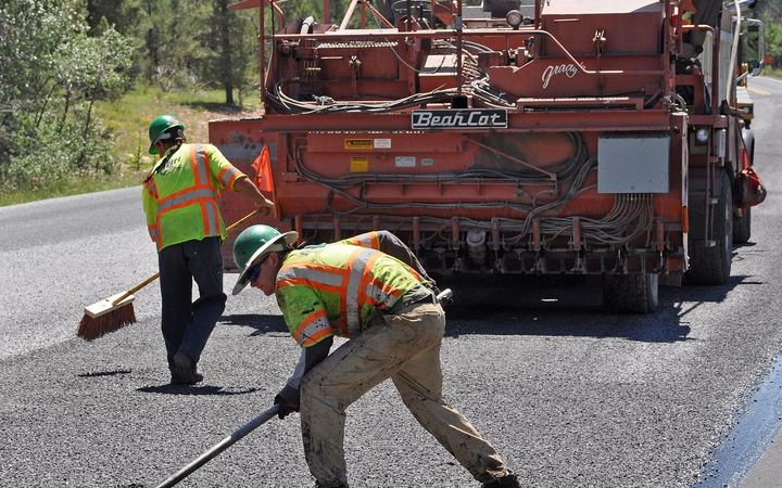 Road crew raking and shoveling fresh hot mix asphalt